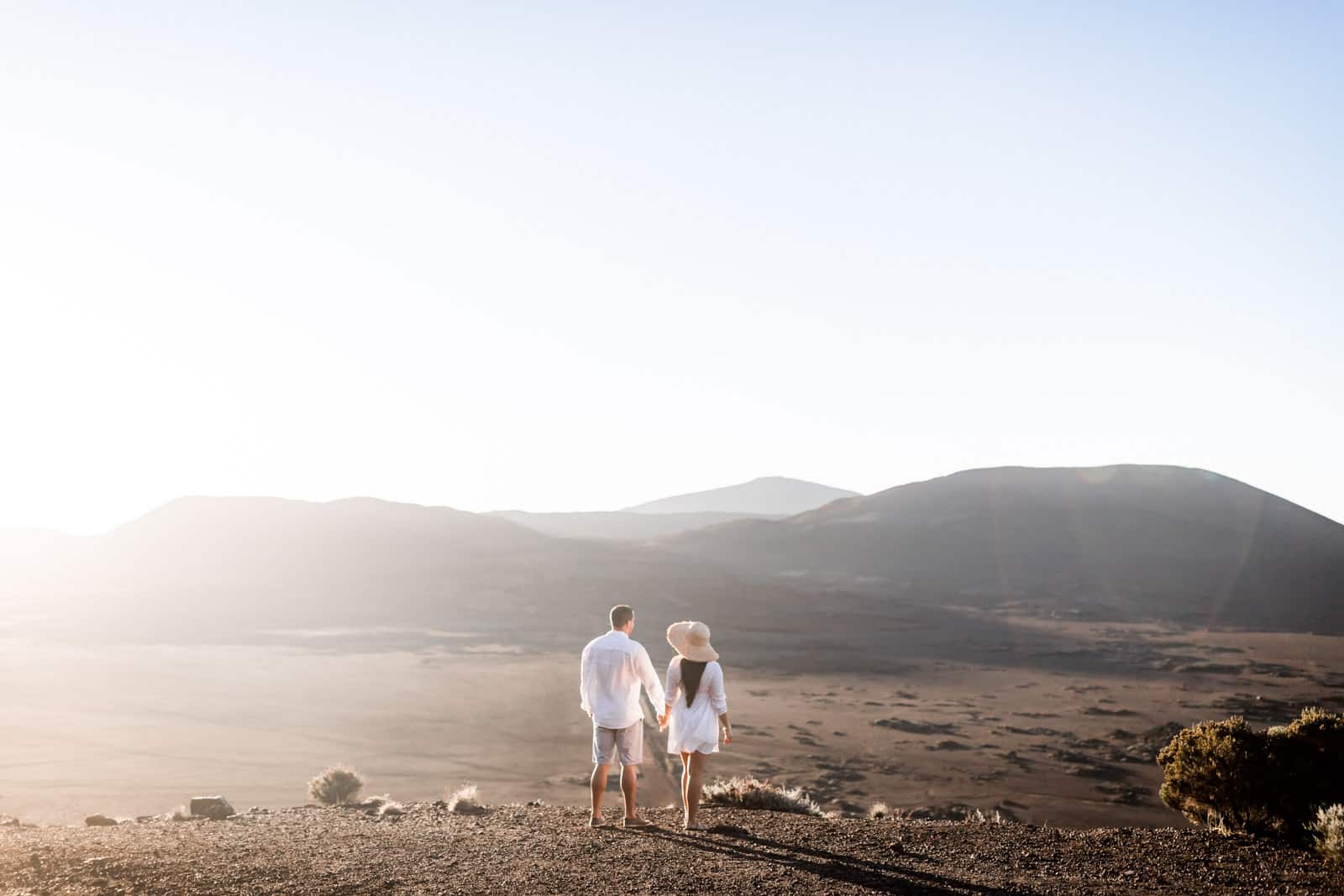 Photographie de Mathieu Dété, photographe de mariage et famille à Saint-Gilles sur l'île de la Réunion 974, présentant un couple qui se tient par la main et qui regarde la route du volcan, le Piton de la Fournaise et la Plaine des Sables