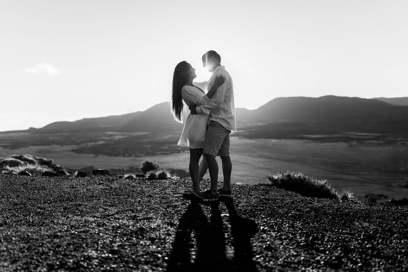 Photographie en noir et blanc de Mathieu Dété, photographe de mariage et couple à Saint-Pierre sur l'île de la Réunion 974, présentant un couple face à face en contre-jour au lever du soleil