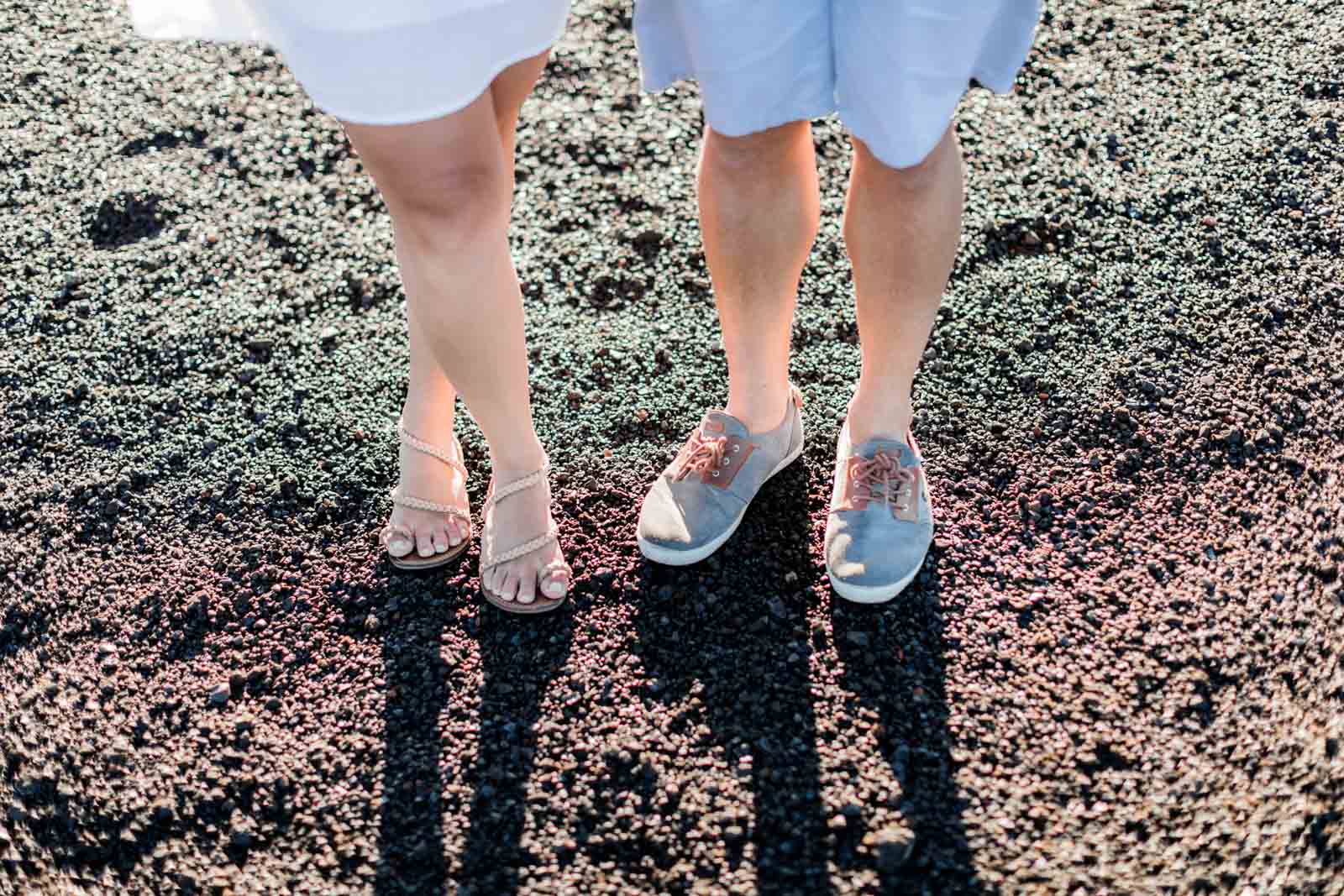 Photographie de Mathieu Dété, photographe de couple et famille à Saint-Leu sur l'île de la Réunion 974, présentant le détail des chaussures d'un couple sur le sol volcanique