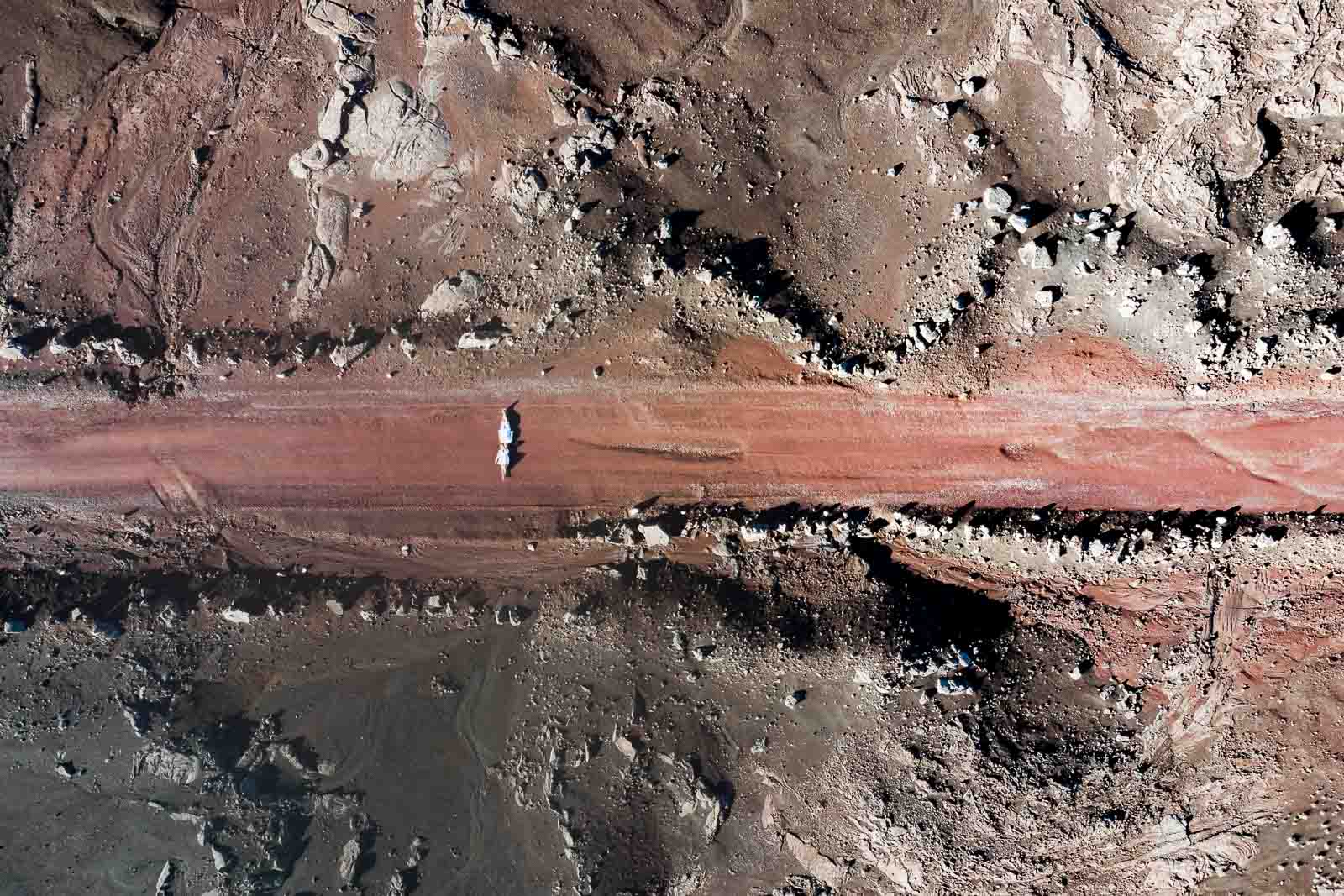 Photographie de Mathieu Dété prise avec un drone, photographe de mariage et famille à Saint-Gilles sur l'île de la Réunion 974, présentant un couple couché sur la route du volcan vu du ciel