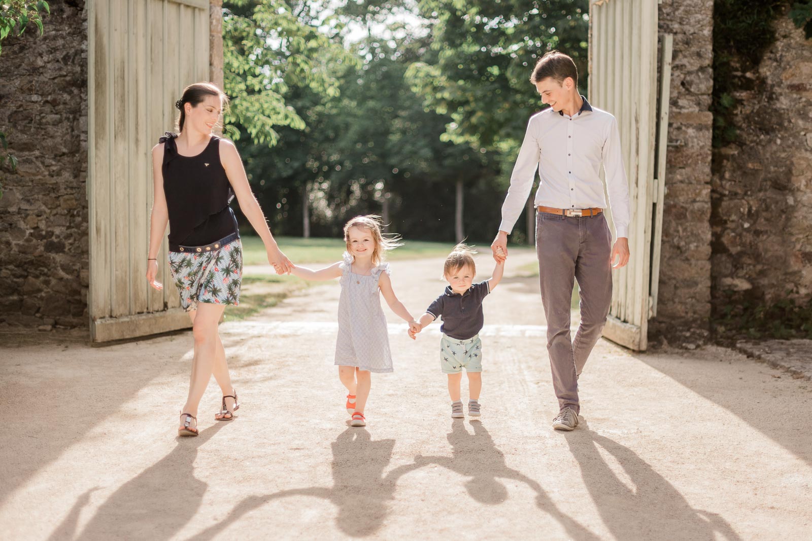 Photographie de Mathieu Dété, photographe de famille, présentant une famille de parents et leurs deux enfants se tenant par la main