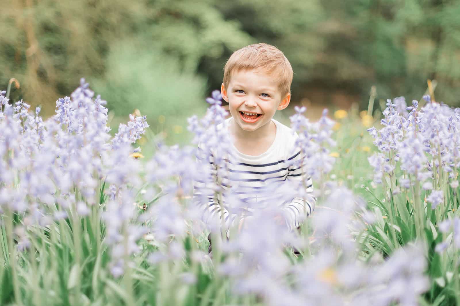 Photographie de Mathieu Dété, photographe de famille, présentant un enfant avec un grand sourire dans les fleurs