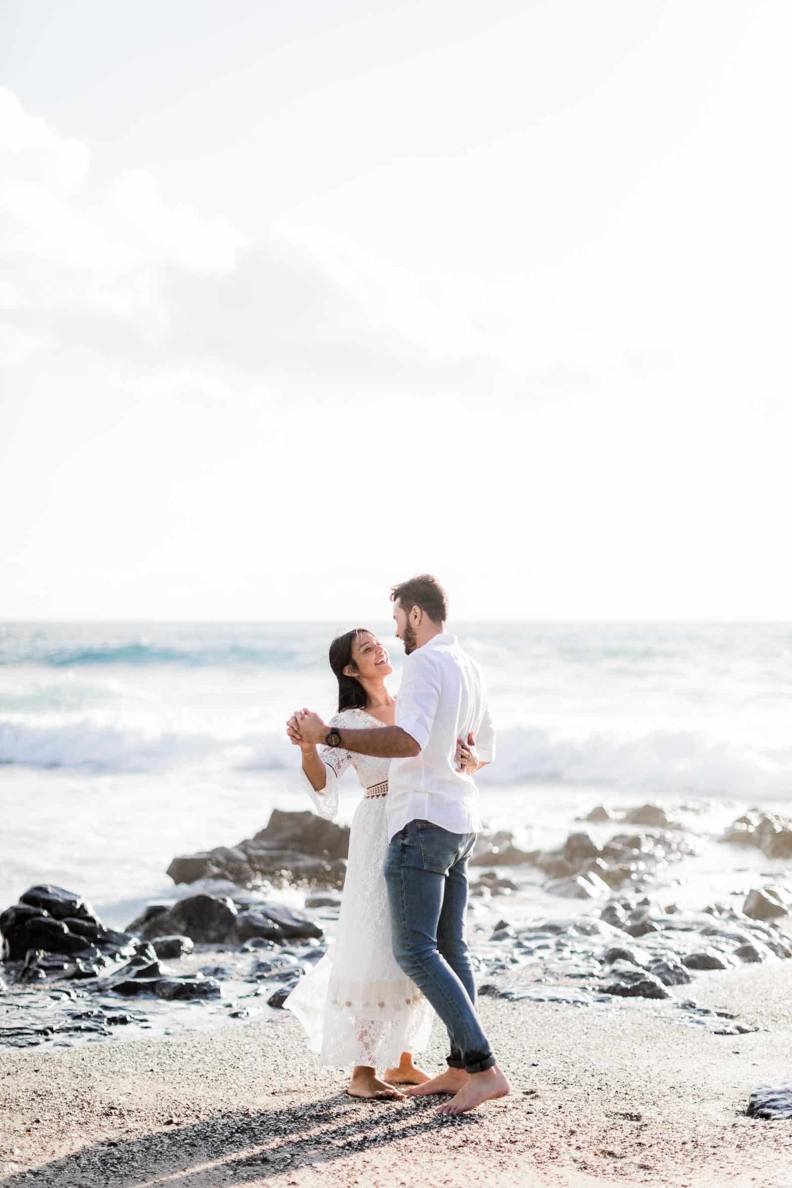 Photographie d'une séance photo au Cap La Houssaye, de Mathieu Dété, photographe de couple et famille à Saint-Denis de la Réunion 974, présentant un couple qui danse les pieds dans l'eau de l'Océan Indien