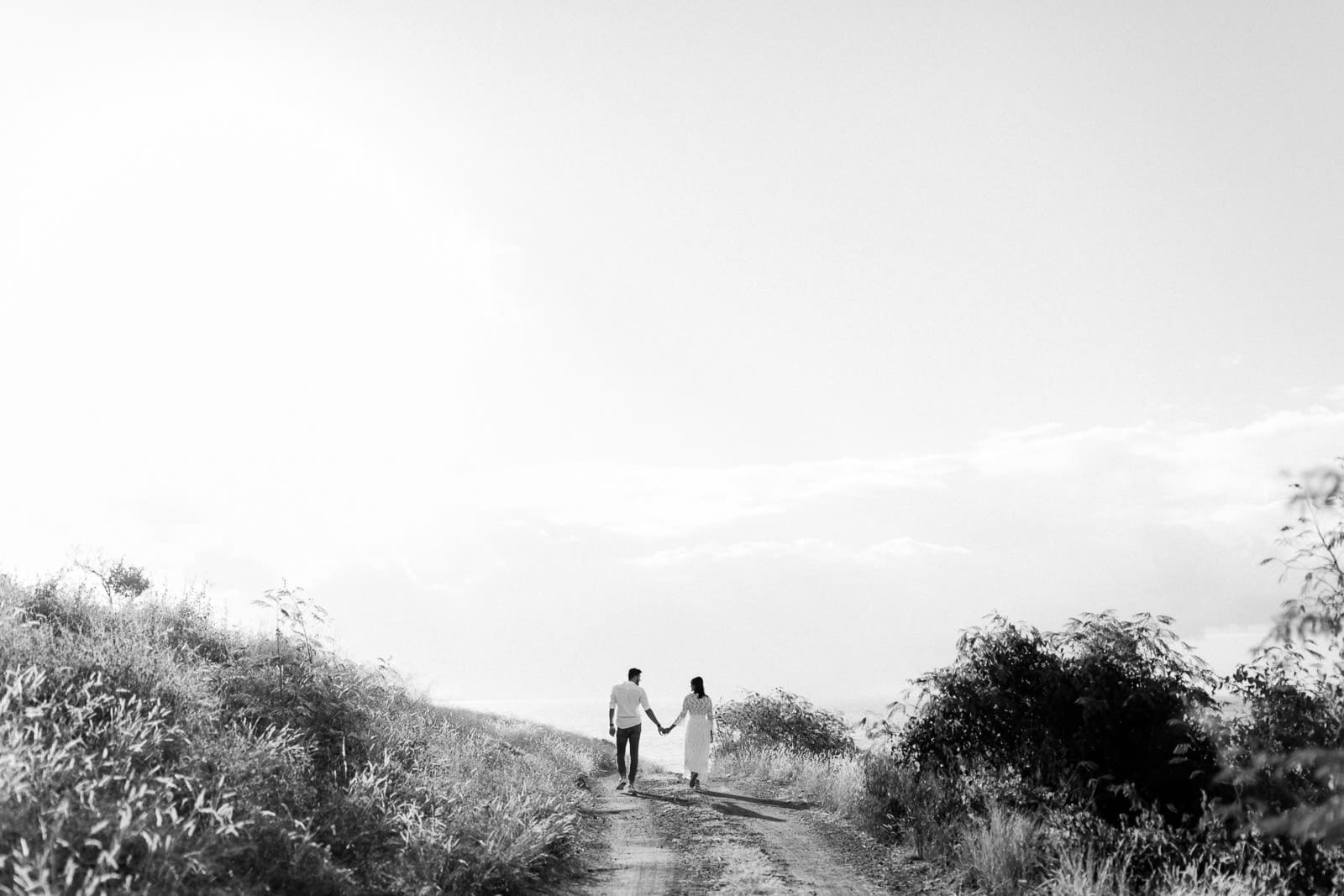 Photographie de Mathieu Dété en noir et blanc, photographe de mariage et famille à Saint-Gilles de la Réunion 974, présentant un couple qui marche dans la savane du Cap La Houssaye, près de Saint-Paul