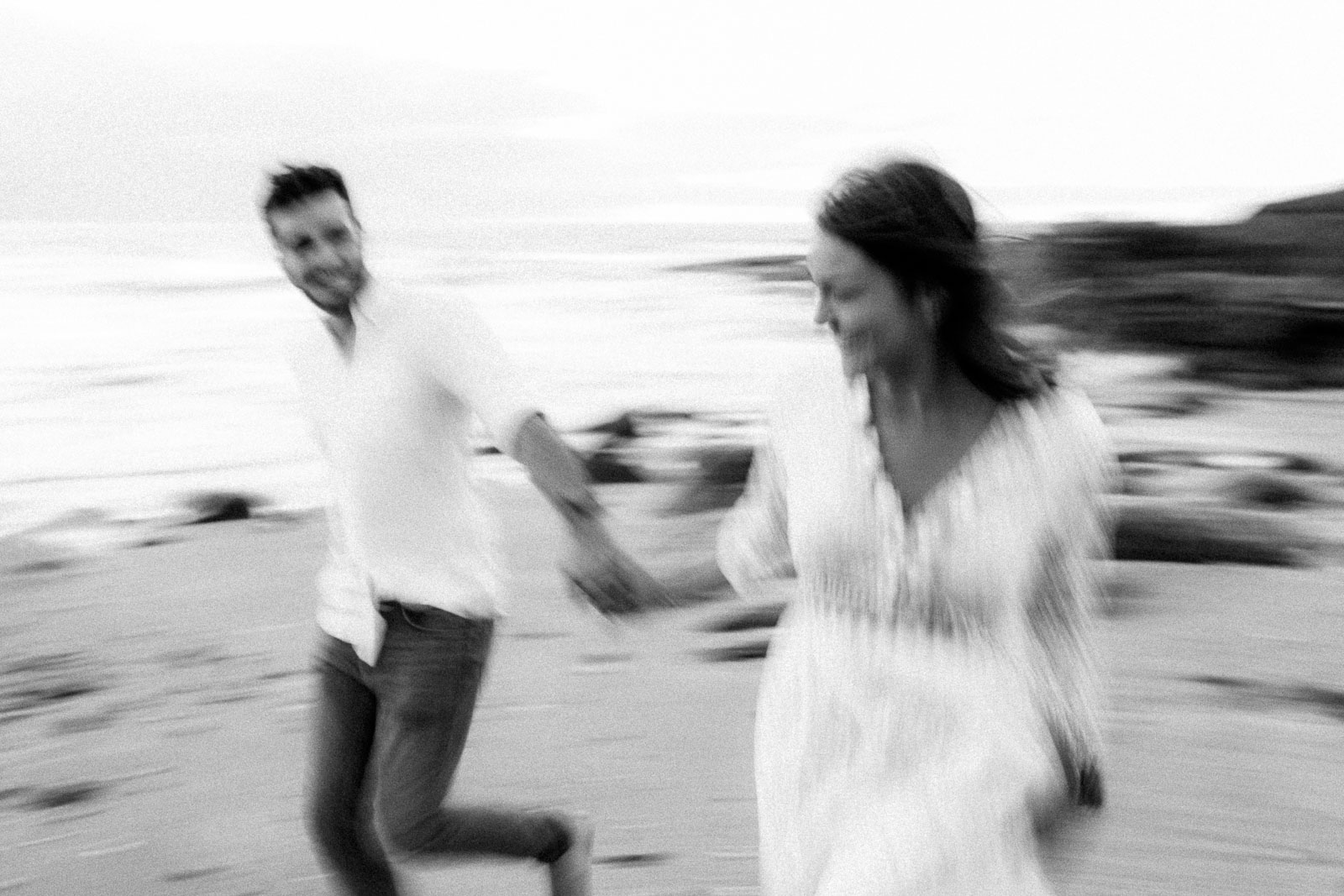 Photographie de Mathieu Dété, photographe de mariage et fiançailles à Saint-Pierre de la Réunion 974, présentant un couple qui court en bord de mer, en noir et blanc