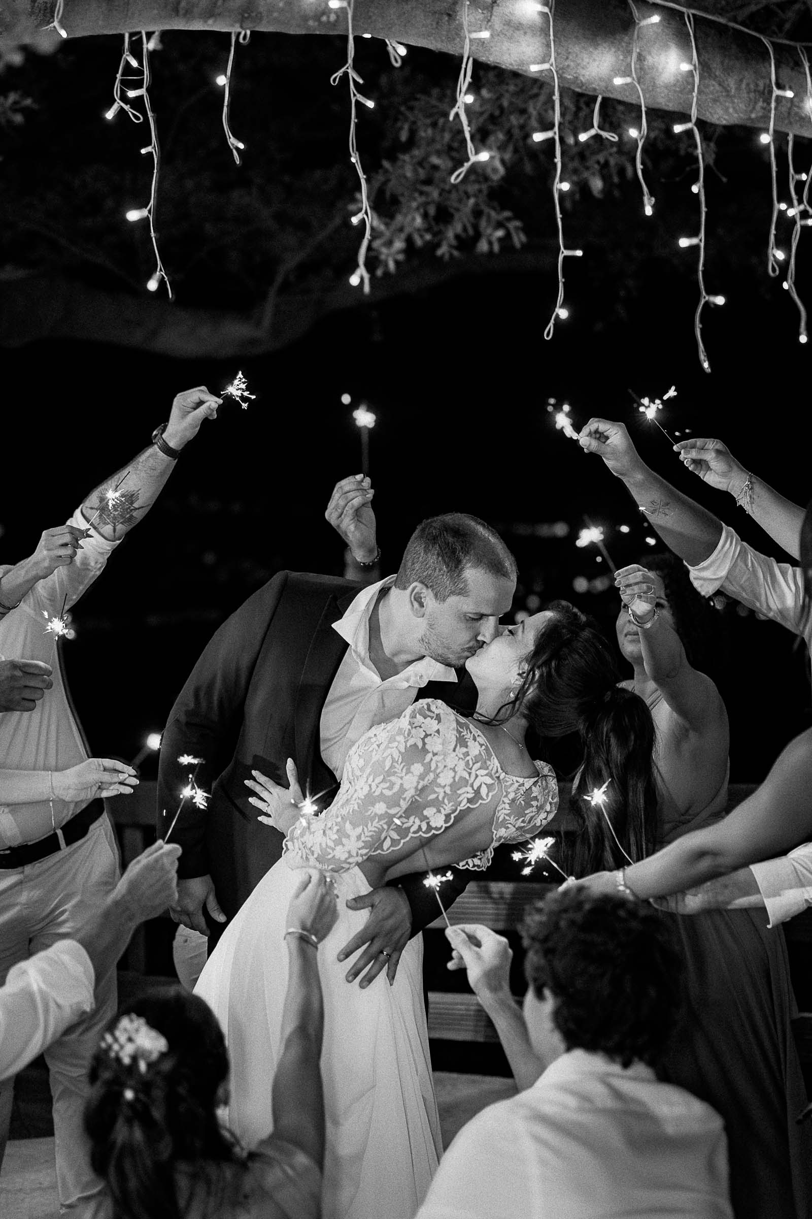 Photographie de Mathieu Dété, photographe de mariage sur l'île de la Réunion 974, présentant les mariés enlacés et entourés par leurs garçons et demoiselles d'honneur et des étincelles