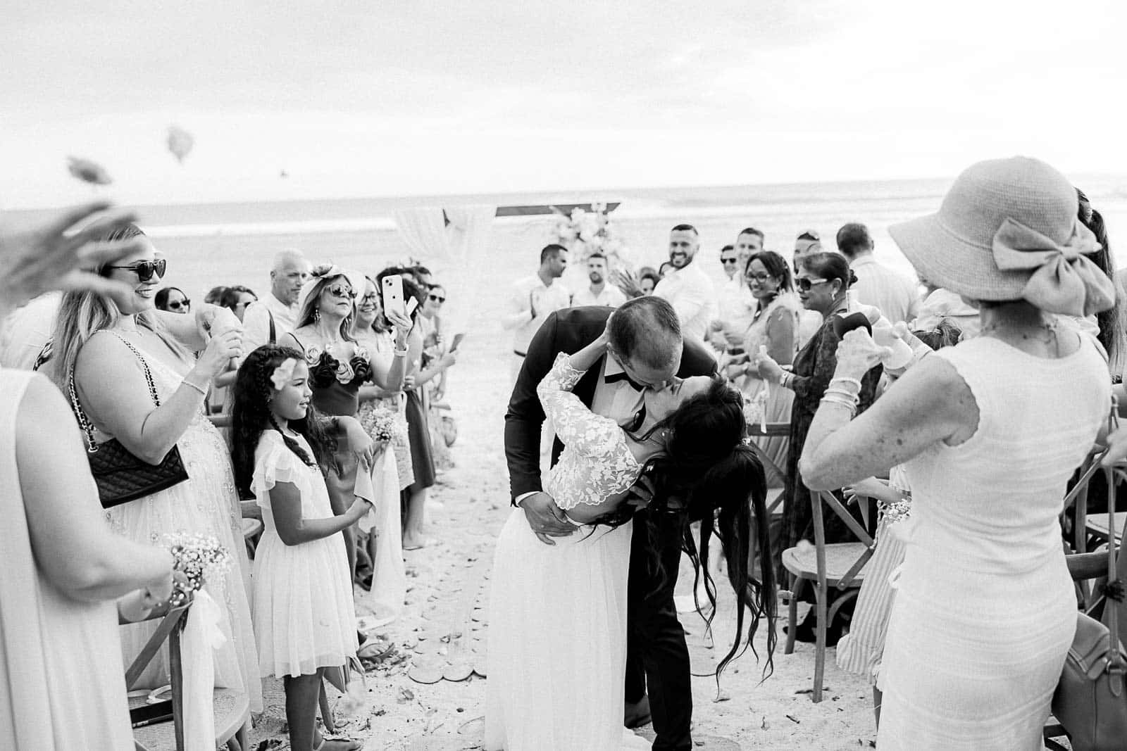 Photographie de Mathieu Dété, photographe de mariage sur l'île de la Réunion 974, présentant un couple de mariés sortant de la cérémonie laïque sur la plage de Saint-Leu