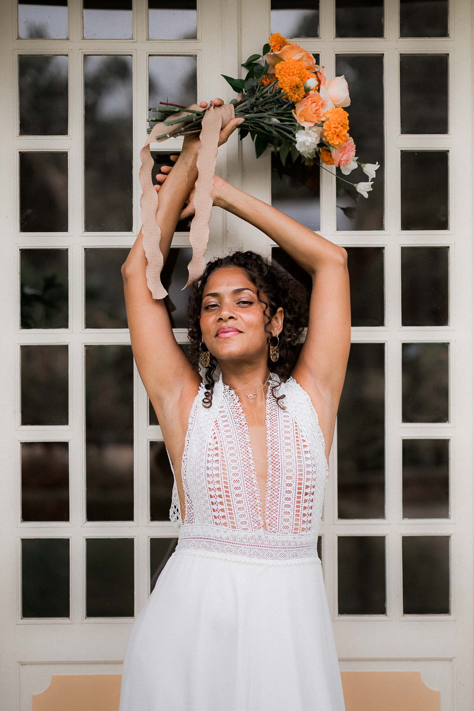 Photographie de Mathieu Dété, photographe de mariage et famille à Saint-Pierre sur l'île de la Réunion 974, présentant une modèle dans une robe de mariée devant la fenêtre de la villa du Jardin Mascarin de Saint-Leu