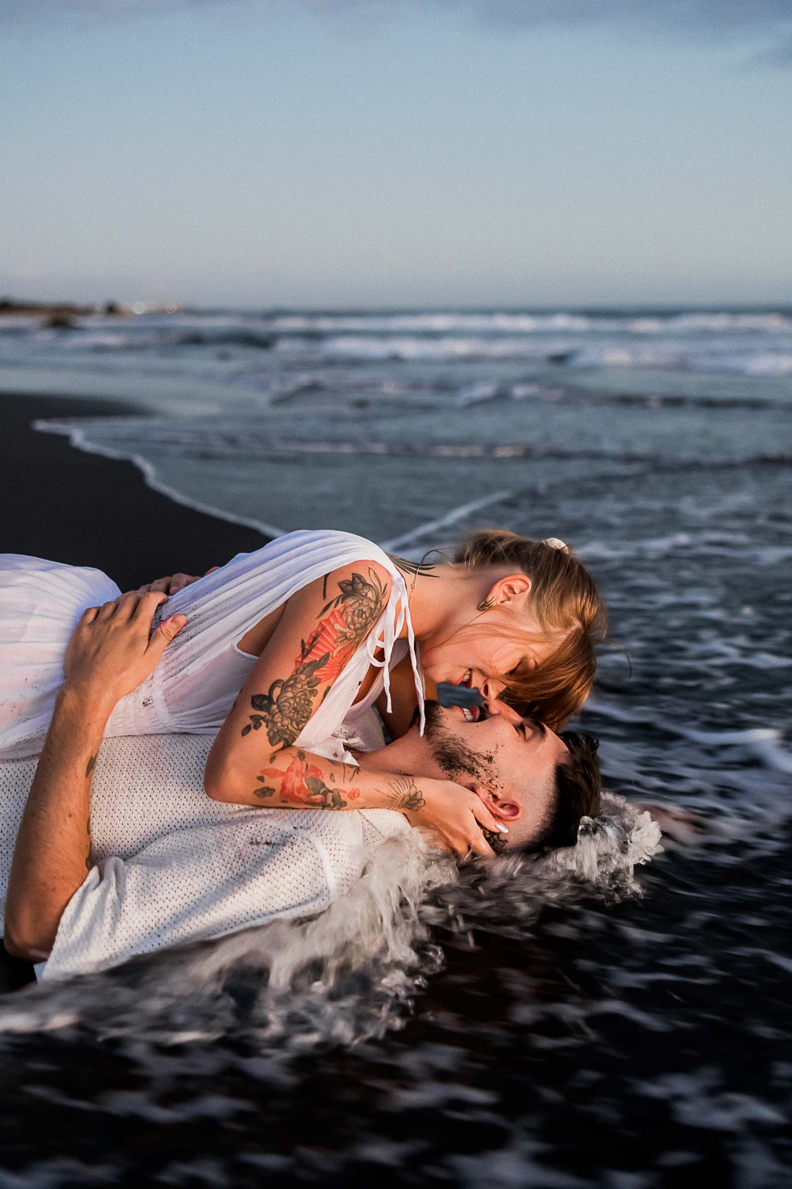 Photographie de Mathieu Dété, photographe de mariage sur l'île de la Réunion 974, présentant un couple allongé dans les vagues sur la plage de la Ravine des Sables, à Etang Salé