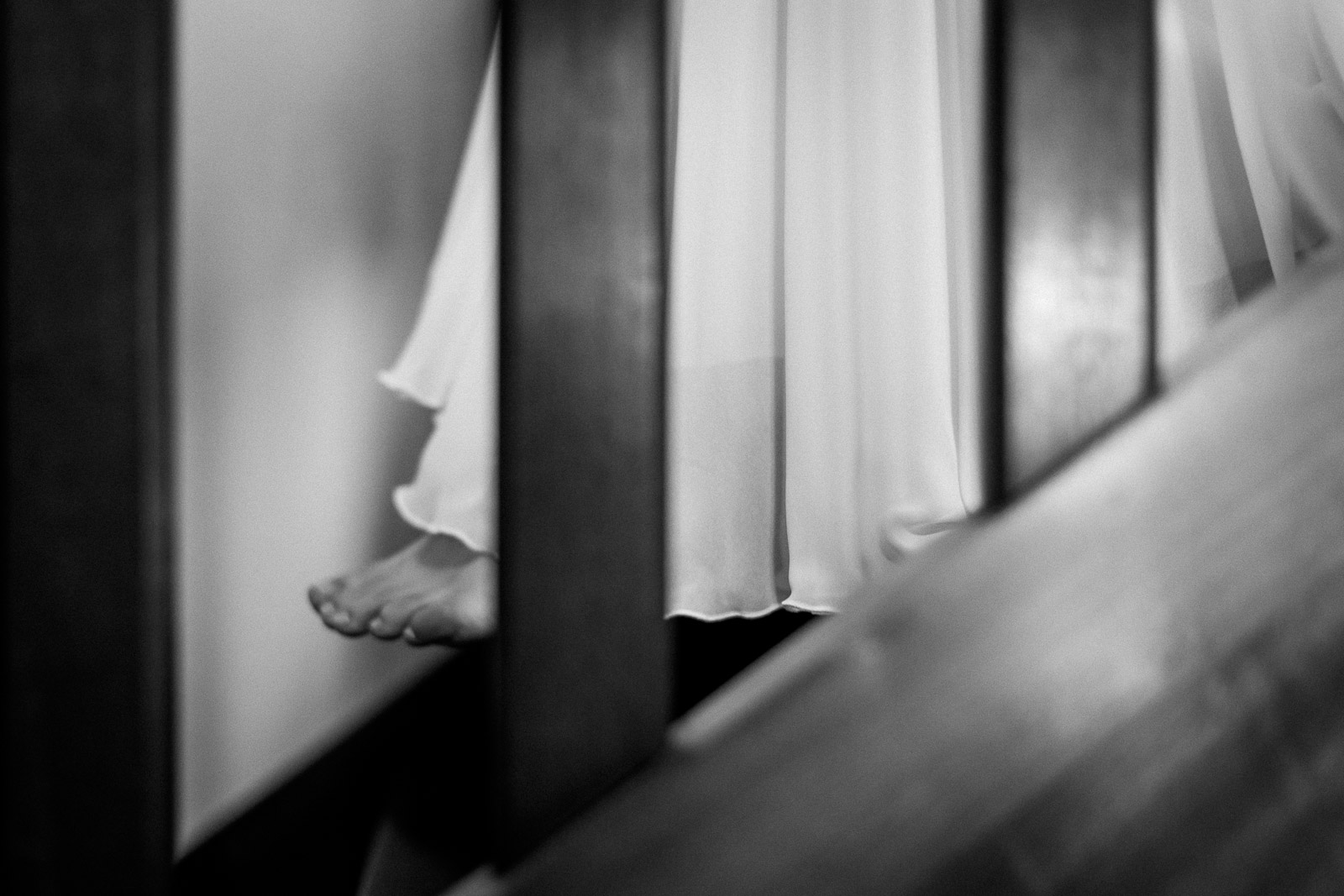 Photographie de Mathieu Dété, photographe de mariage et grossesse à Sainte-Marie, sur l'île de la Réunion 974, présentant les détails de la robe et de la mariée qui marche pour descendre les escaliers, en noir et blanc