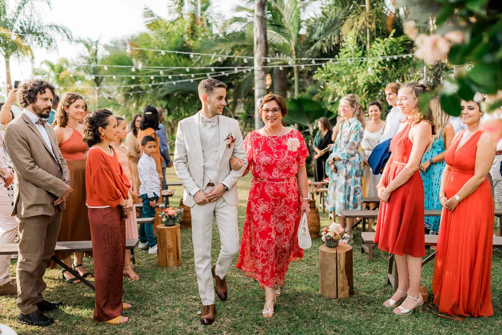 Photographie de Mathieu Dété, photographe de mariage et grossesse à Sainte-Marie, sur l'île de la Réunion 974, présentant l'entrée du marié dans la cérémonie laïque, aux bras de sa maman