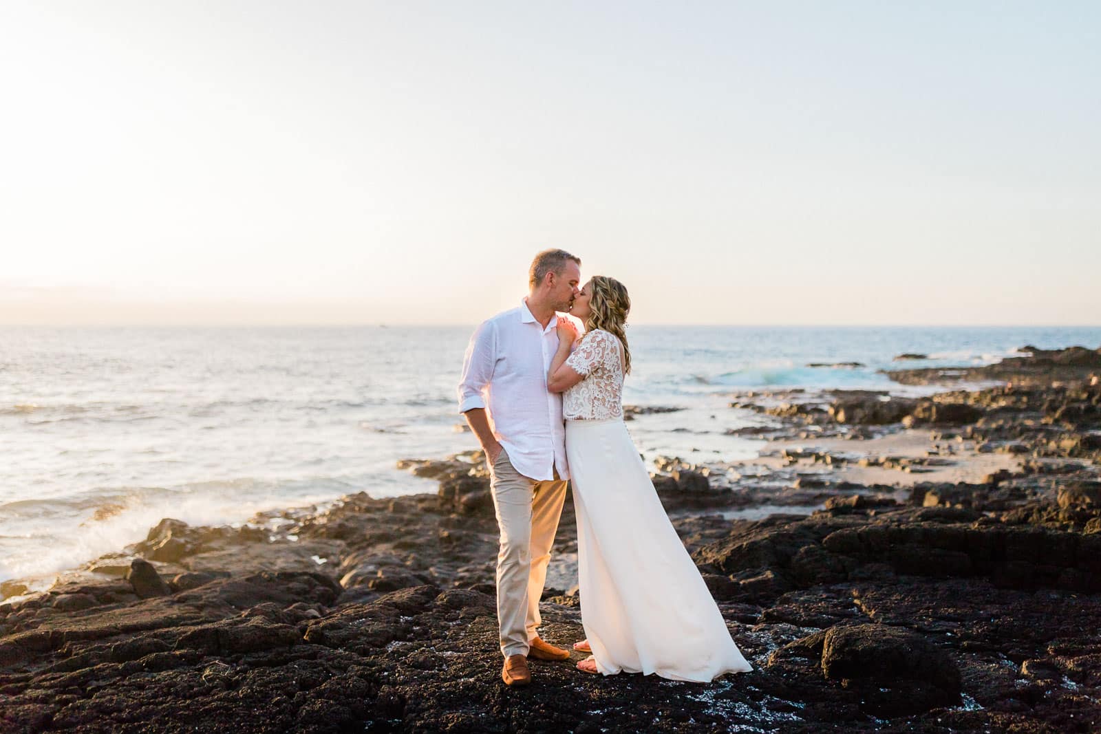 Photographie de Mathieu Dété, photographe de mariage à la Réunion, présentant un portrait d'un couple de mariés au soleil couchant au Cap La Houssaye à Saint-Paul