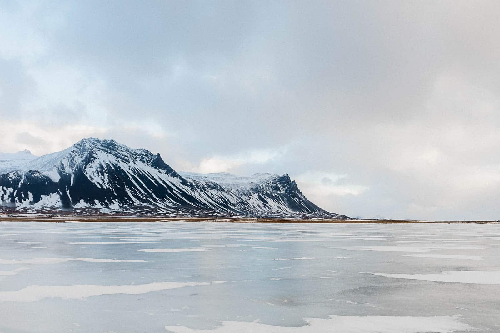 Photographie de Mathieu Dété, photographe de mariage et de voyage à la Réunion, présentant une photo de montagnes enneigées devant un lac de glace, lors d'un voyage en Islande