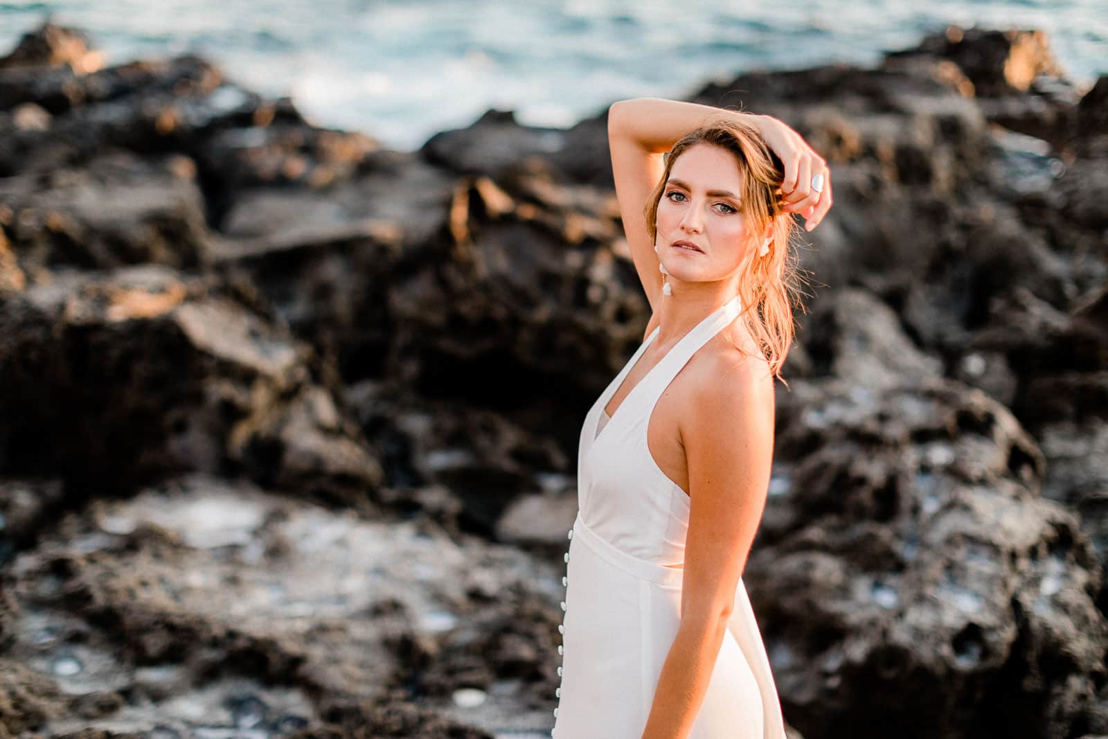 Photographie de Mathieu Dété, photographe de mariage, de mode et de fiançailles à Saint-Paul sur l'île de la Réunion 974, présentant Emma, mannequin, en robe de mariée de la marque Maison Mananne, dans les roches volcaniques de la Pointe au Sel