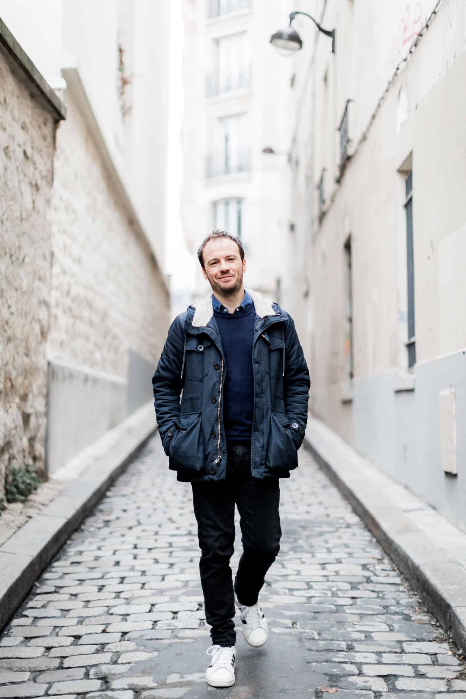 Photographie de Mathieu Dété, photographe de mariage et portrait sur l'île de la Réunion (974), présentant un portrait de Benoît Dorémus à Montmartre en marchant dans une ruelle