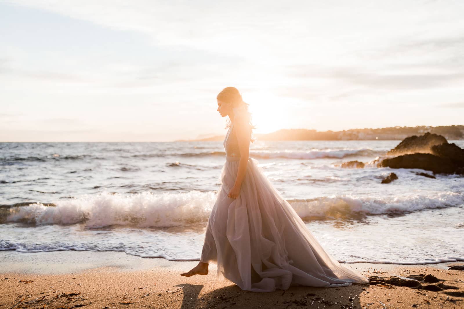 Photographie de Mathieu Dété, photographe de mariage et couple à Saint-Denis de la Réunion (974), présentant un portrait de la mariée qui marche sur la plage au coucher de soleil en bord de mer